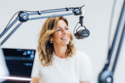 Een vrouw wil een nieuwe podcast starten en zit voor een microfoon