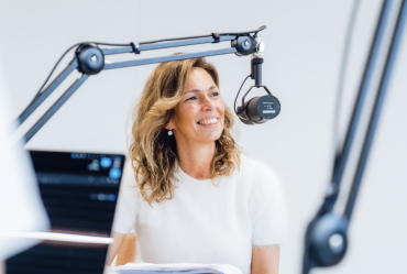 Een vrouw wil een nieuwe podcast starten en zit voor een microfoon