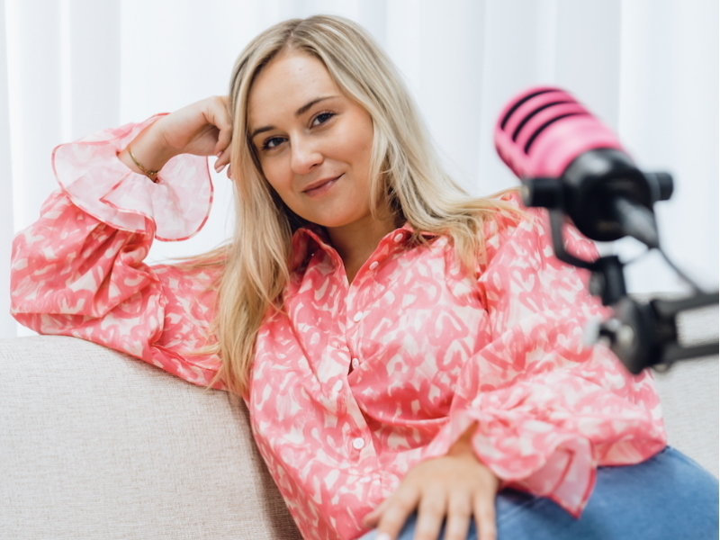 een vrouw zit in een zetel en wil haar podcast verbeteren en vraagt advies 	aan 50 Koffies podcast producties