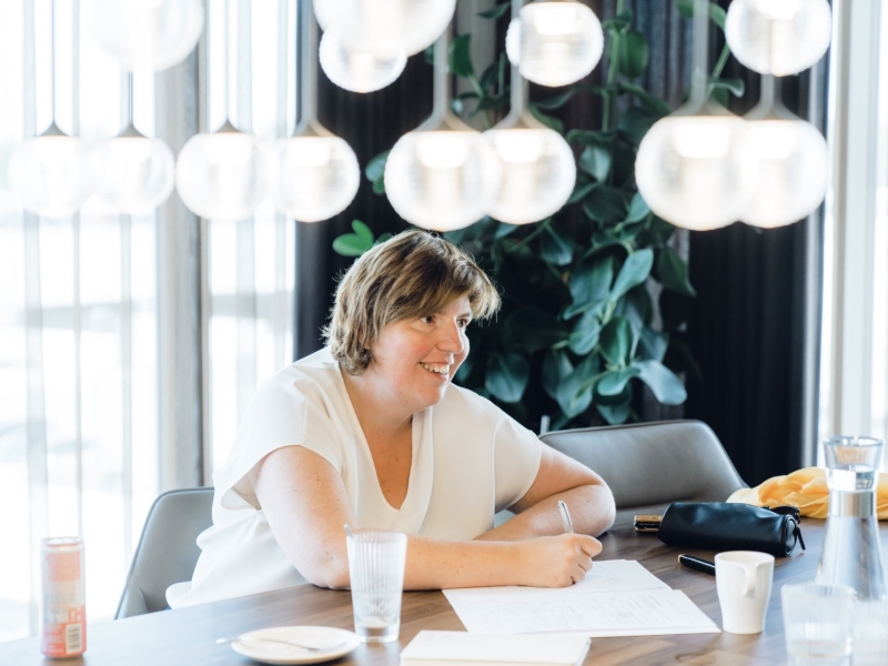 een vrouw schrijft vrolijk in haar schrift omdat ze een podcast gaat laten maken