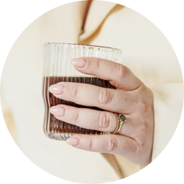 een vrouwenhand met een koffie in de hand wil graag een kennismakingsgesprek inplannen