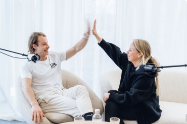 een man en een vrouw zitten in een zetel en zijn samen een podcast aan het maken met 50 koffies producties