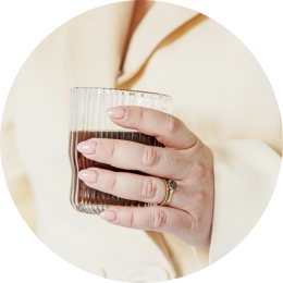 een vrouwenhand met een koffie in de hand wil graag een kennismakingsgesprek inplannen