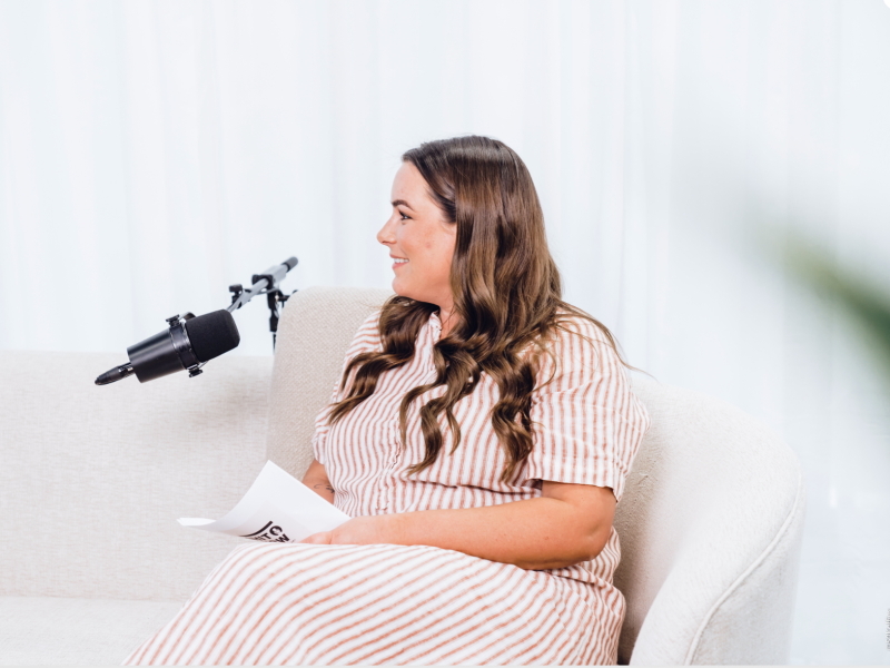 een vrouw zit in een zetel en is bezig met podcast te maken
