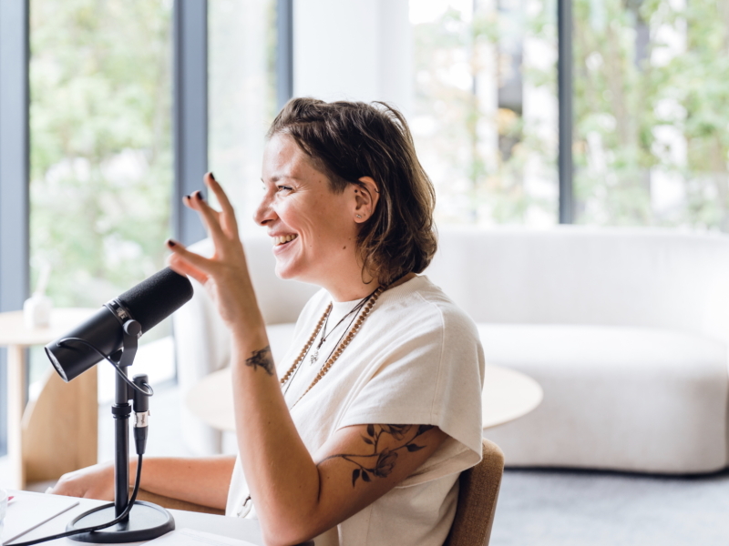 een vrouw is met enthousiasme een podcast aan het maken met 50 Koffies producties