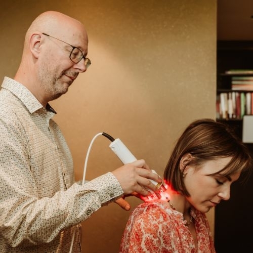 Acupuncturist past laseracupunctuur toe bij een patiënt voor een niet-invasieve behandeling.