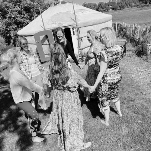 Vrouwen in een cirkel buiten op een grasveld, houden elkaars hand vast