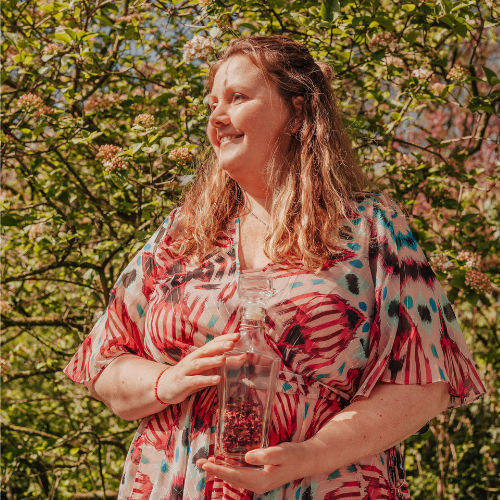 Vrouw in het park, bij een bloeiende struik met roze bloemen