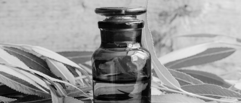 Donkergekleurd glazen flesje met wilgenbladeren