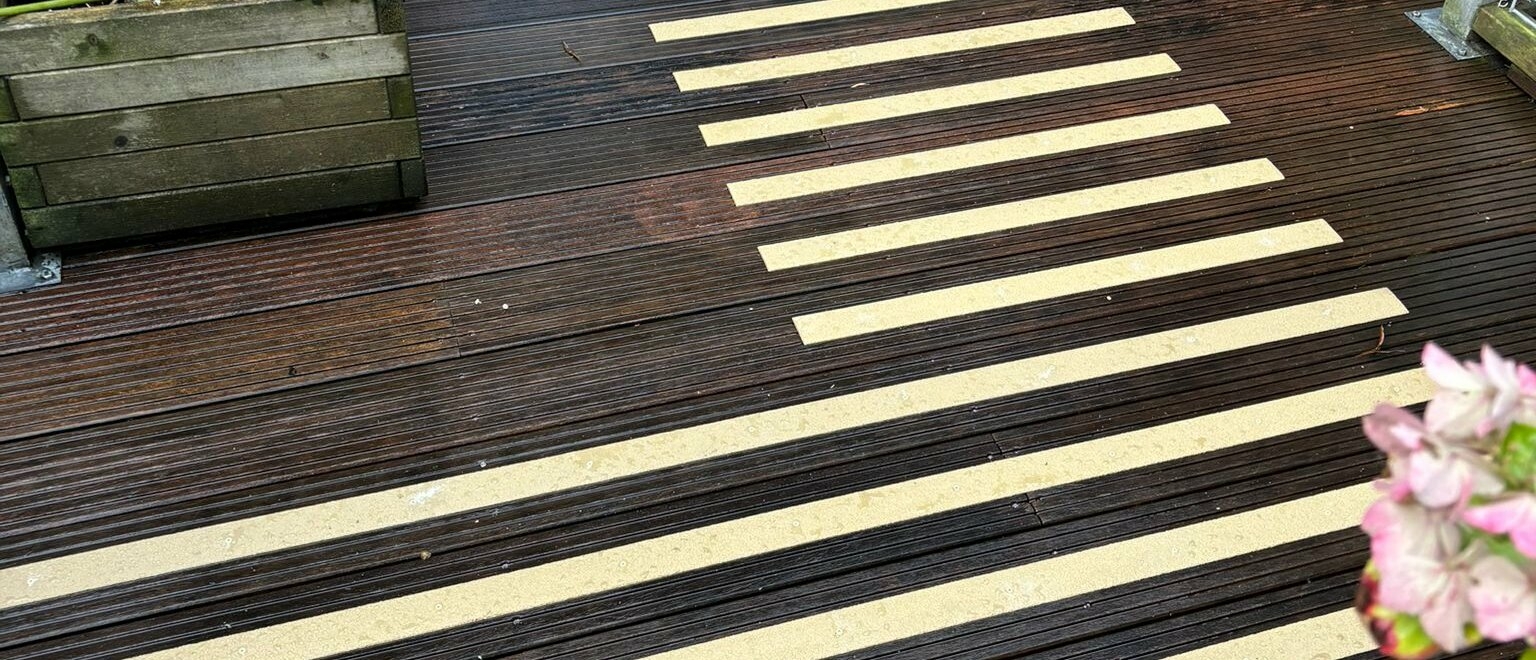 Gladde vlonderplanken hardhout Natte hardhouten vlonderplanken met gele antislip stroken op de looproute naar de achterdeur