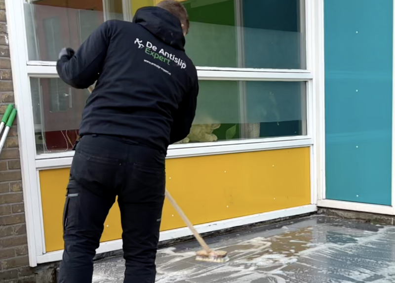 Marciano Simonis van De Antislip Expert schrobt de entree goed voordat hij de antislip coating gaat aanbrengen