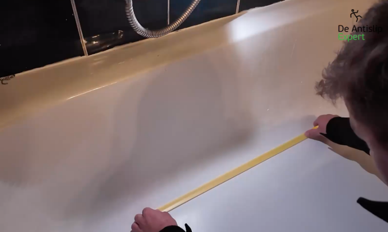 Marciano brengt antislip tape aan in een badkuip ter voorbereiding op ASE Sanigrip antislipcoating