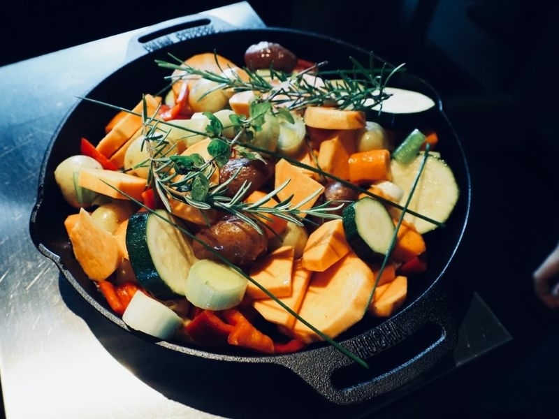Kleurrijke seizoensgroenten met rozemarijn in een gietijzeren pan tijdens de BBQ workshop bij Bedstay op 8 in Dalen