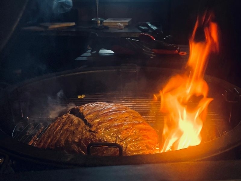 Groot stuk vlees grillen op open vuur tijdens de BBQ-workshop bij Bedstay op 8 in Dalen