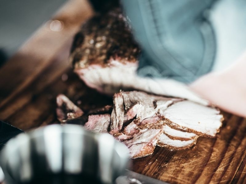 Gegrild vlees wordt aangesneden op een houten snijplank tijdens de BBQ-workshop bij Bedstay op 8