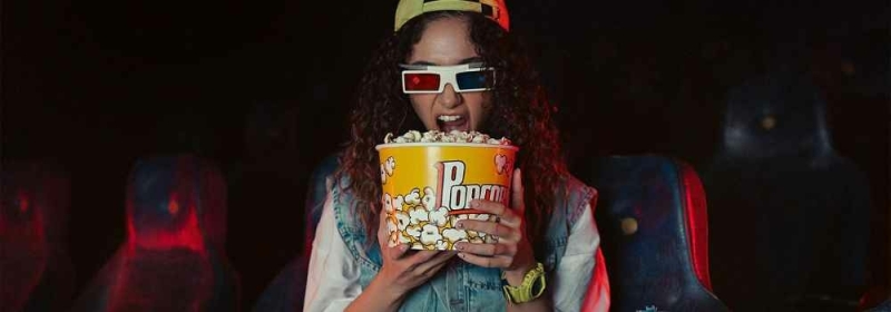 Vrouw met 3D bril en popcorn in bioscoop