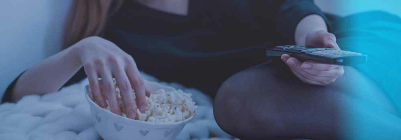 Vrouw met bak popcorn en afstandsbediening