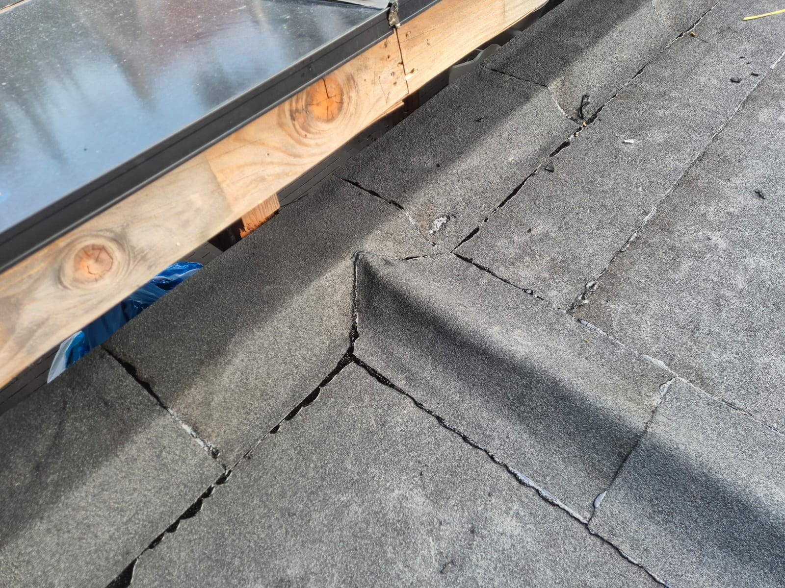 Detail van een plat bitumen dak met scheuren rond de opstand en houten constructie, een veelvoorkomend risico op lekkage bij platte daken.