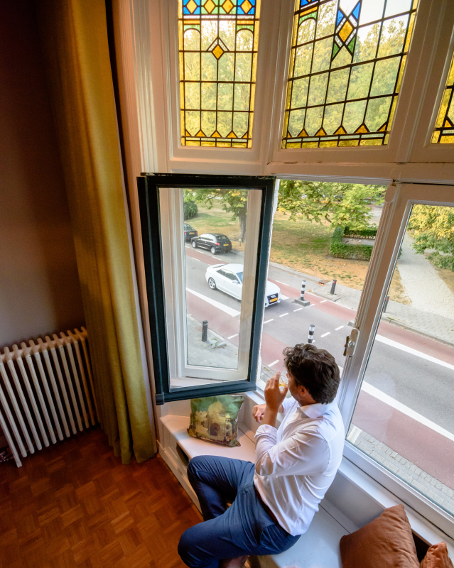 Sven in his favorite spot in the livingroom, sipping a drink, staring at the park across the house