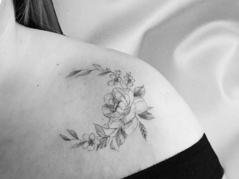Fine line bloemen tattoo op schouder
