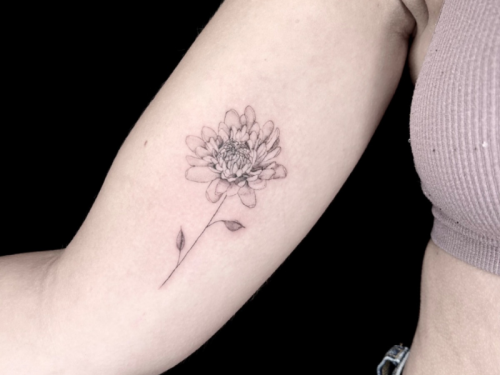 Fine line tattoo bloem op bovenarm