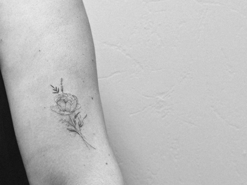 Fine line tattoo bloemen boeket op bovenarm