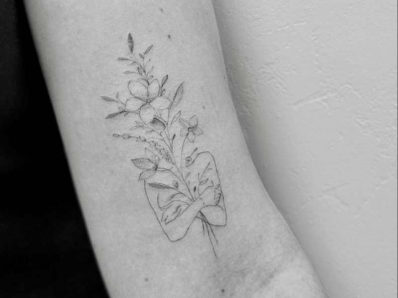 Fine line tattoo met bloemen en vrouw