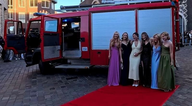 Vriendengroep stapt uit een rode brandweerauto bij een feestlocatie – verrassend vervoer dat zorgt voor glimlachen en een onvergetelijke start van het feest.
