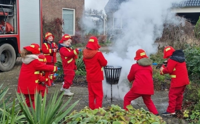 Kinderen oefenen met het blussen van een vuurkorf tijdens ons familiedag arrangement in Gelderland en Noord-Brabant, begeleid door de brandweerauto-crew.