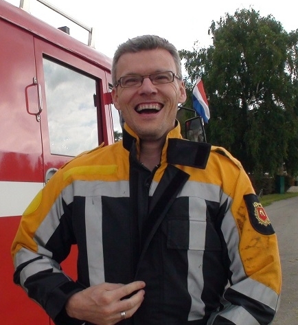 een lachende persoon die een verjaarsdagsfeest geeft met de brandweerwagen