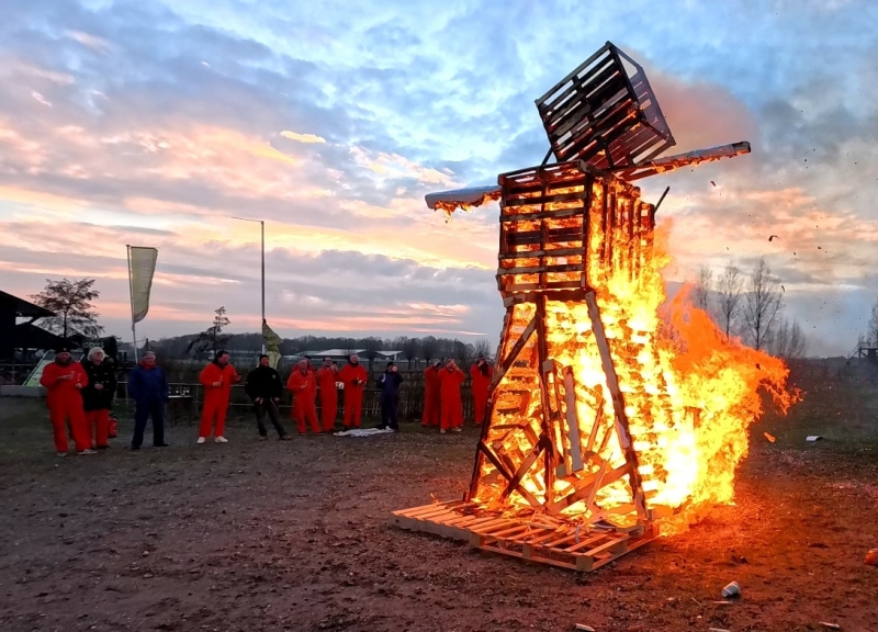Team beleeft het hoogtepunt van de Burning Man workshop terwijl de zelfgebouwde reuzenpop in vlammen opgaat. Creatief en spectaculair bedrijfsuitje met vuur en teamwork.