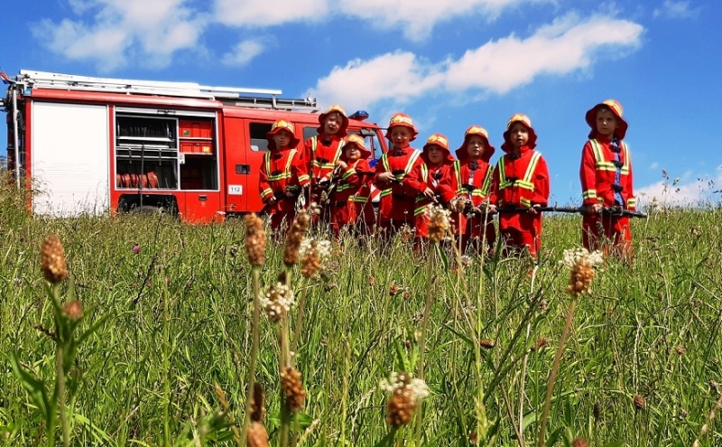 Een groep kinderen beleeft een avontuurlijk brandweer kinderfeestje bij de brandweerauto, vol teamwork, reddingsmissies en plezier.