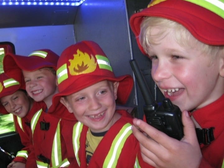 Kinderfeestje brandweerauto met kinderen en walkie talkie Blije kinderen tijdens een kinderbrandweerfeestje in een brandweerauto met walkie talkie, een actief en onvergetelijk kinderfeestje vol plezier en avontuur