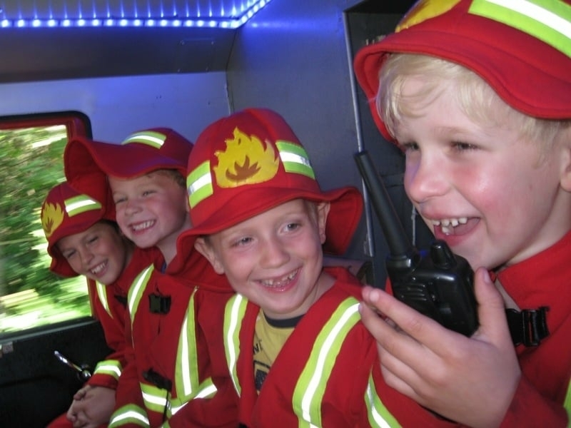 Kinderfeestje brandweerauto met kinderen en walkie talkie Blije kinderen tijdens een kinderbrandweerfeestje in een brandweerauto met walkie talkie, een actief en onvergetelijk kinderfeestje vol plezier en avontuur