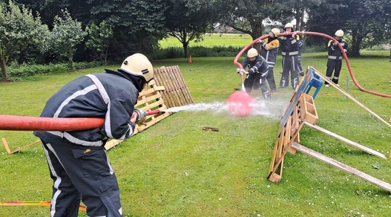 Teambuilding bij de brandweer in Gelderland met teams die samenwerken tijdens een voetbalspel met brandslangen