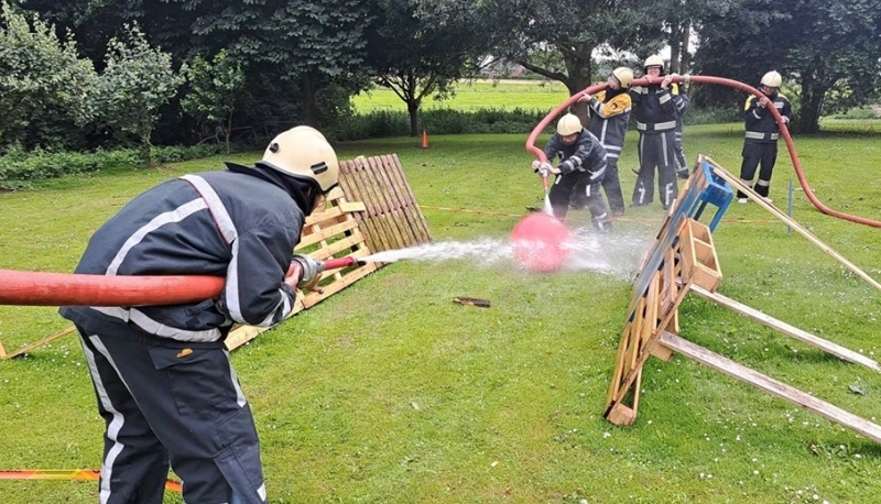 Teambuilding bij de brandweer in Gelderland met teams die samenwerken tijdens een voetbalspel met brandslangen