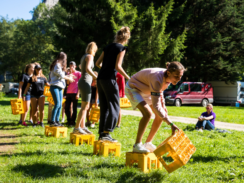zonnig samenwerken winnen kratjes spellen teamwork teambuilding bomen grasveld schoolkamp introkamp groepswerk