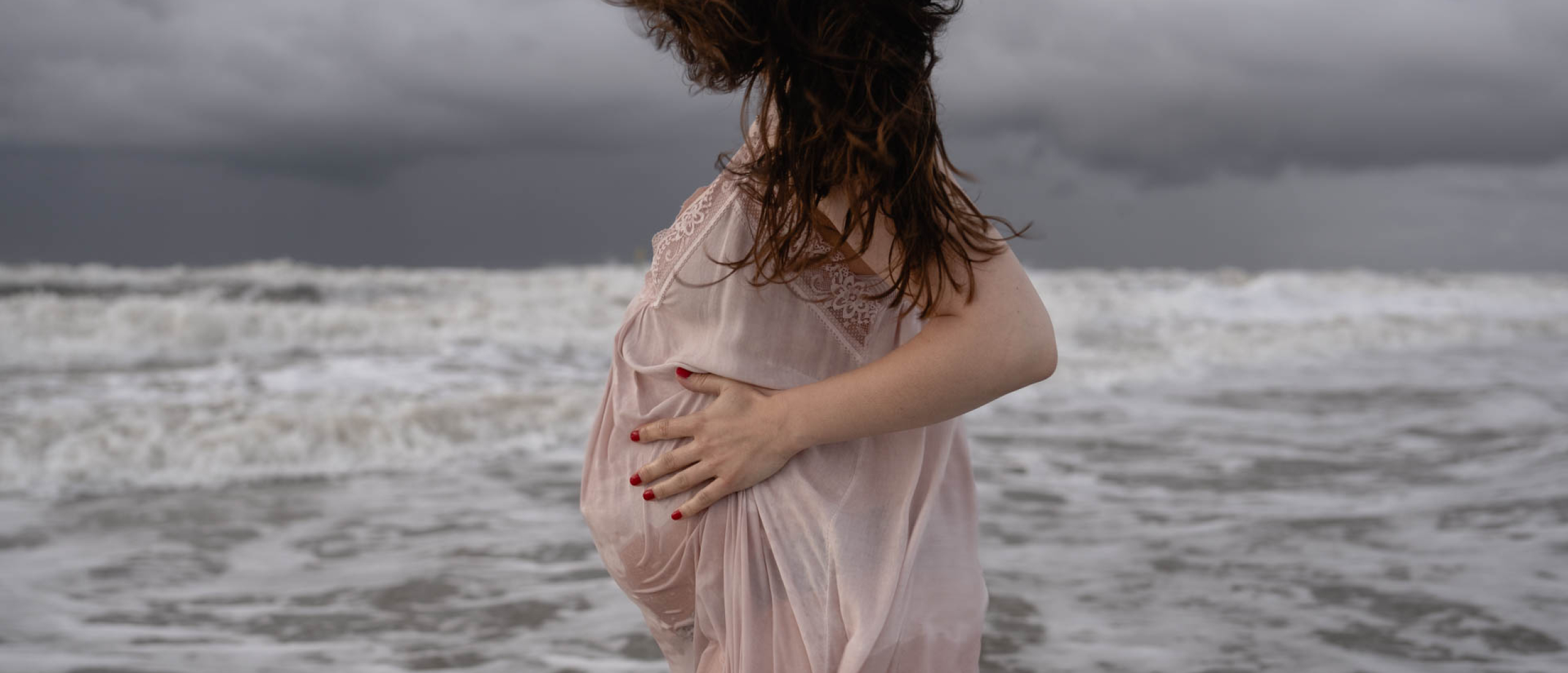 Toffe beelden van je zwangere buik in de woeste zee met zonsondergang