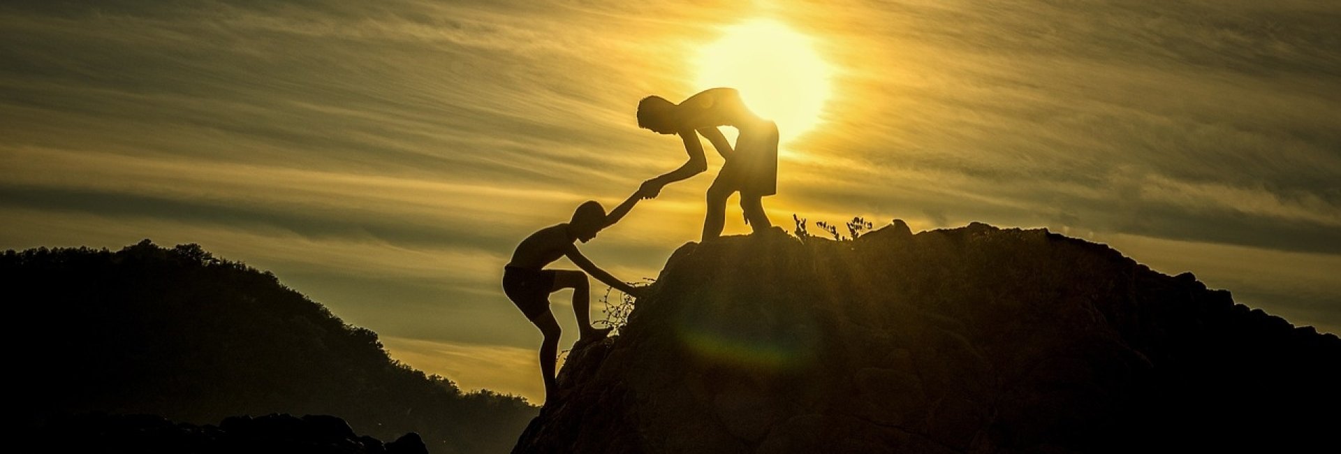 A person helping another person onto a rock