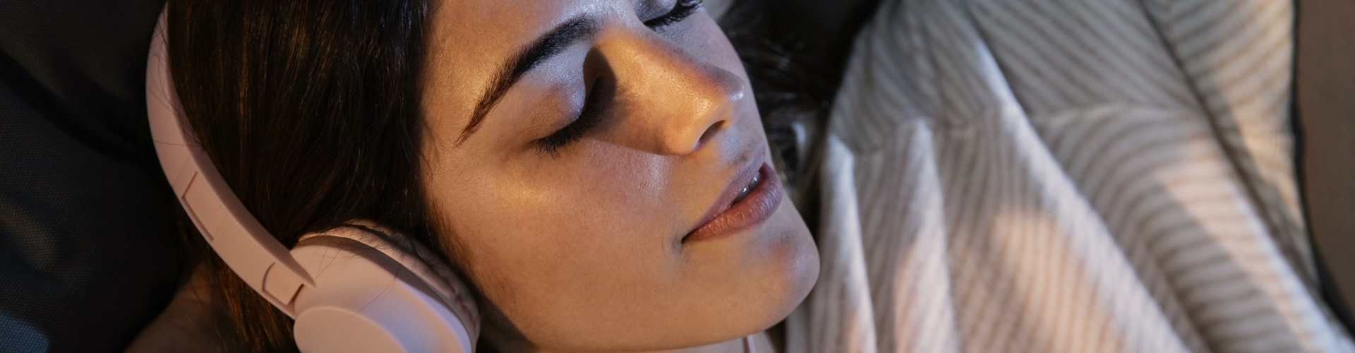 woman-using-headphones-music-home-bed