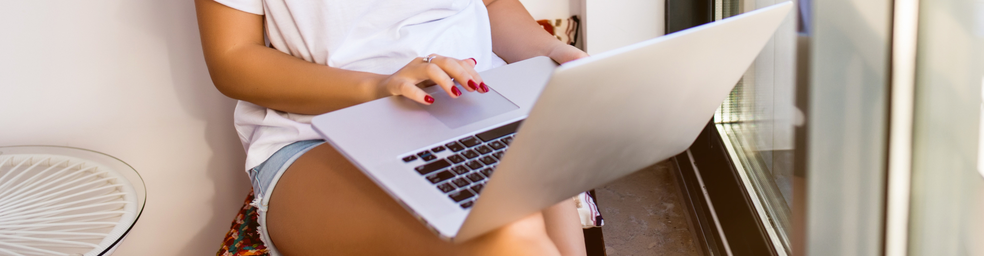 young-smiling-brunette-girl-is-sitting-modern-chair-near-window-light-cozy-room-home-she-is-working-laptop-relaxing-atmosphere