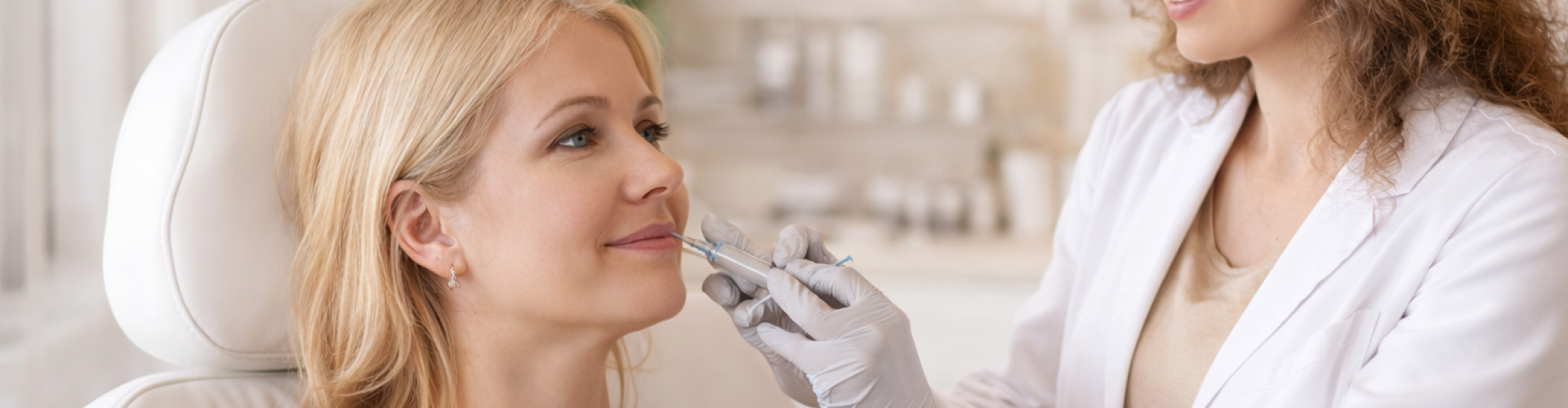 Subtiele behandeling van neus-lippenplooien in een rustige kliniek Cosmetisch arts voert een subtiele fillerbehandeling uit bij de neus-lippenplooi van een ontspannen vrouw in een lichte, professionele behandelruimte