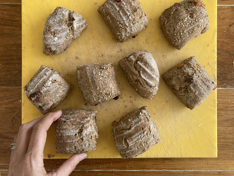 oerbonkjes liggend met hand Marije op gele broodplank - Marije Bakt Brood