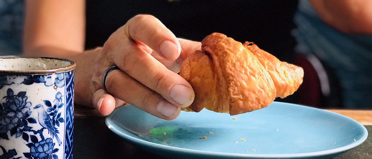 Vegan croissant met hand en kopje thee - Marije Bakt Brood