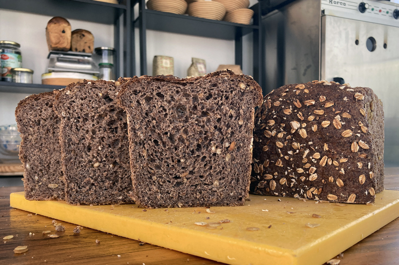 Volkoren meergranenbrood sneetjes- Marije Bakt Brood sneetjes op snijplank, bakoven haverkorrels bakkerij