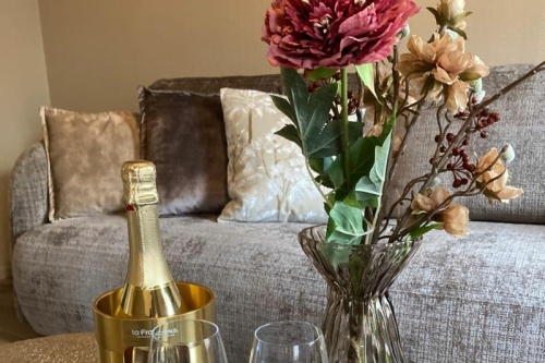 Sfeervolle zithoek in de suite met champagne op ijs en verse bloemen bij De La Frontière Bed & Borrelbistro in Slenaken