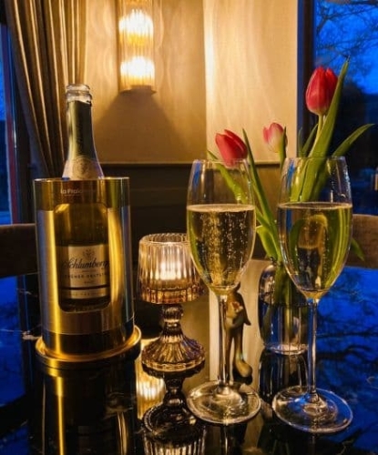 Champagneglazen en fles op tafel in sfeervolle setting bij De La Frontière Bed & Borrelbistro in Slenaken