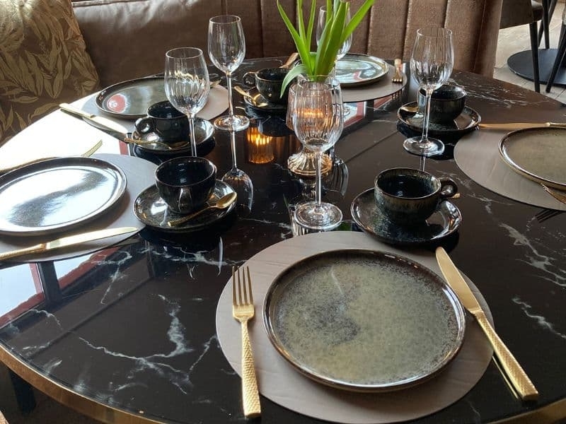Sfeervolle gedekte tafel met servies en bloemen bij De La Frontière Restaurant Bed & Borrelbistro in Slenaken