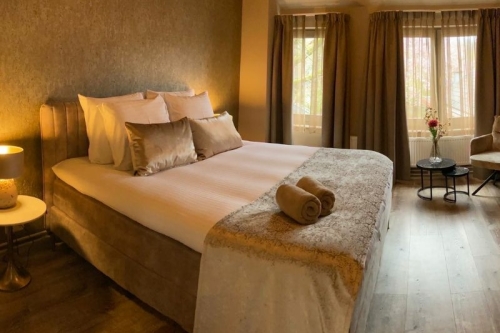 Ruim ingerichte comfortkamer met luxe boxspring, zithoek en natuurlijk licht bij De La Frontière Bed & Borrelbistro in Slenaken