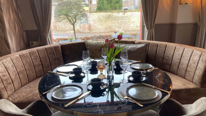 Luxe ronde tafel met gouden bestek en tulpen in de borrelbistro van De La Frontière in Slenaken